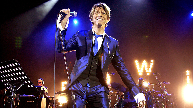 David Bowie onstage smiling holding microhphone