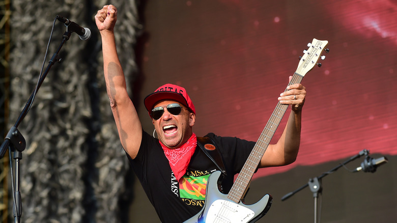 Tom Morello with guitar raising fist onstage