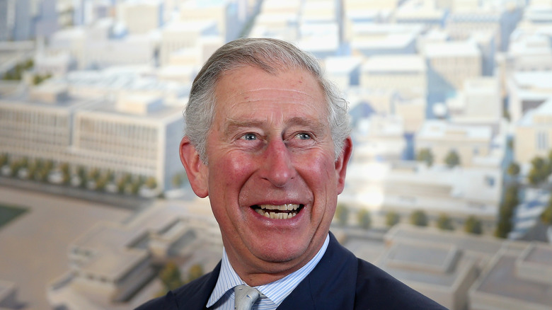 Prince Charles in front of an architectural drawing smiling