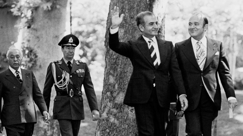 The Shah waves while walking with supporters