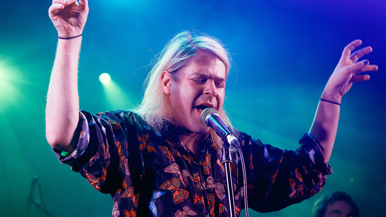 ariel pink holding hands up and singing with eyes closed