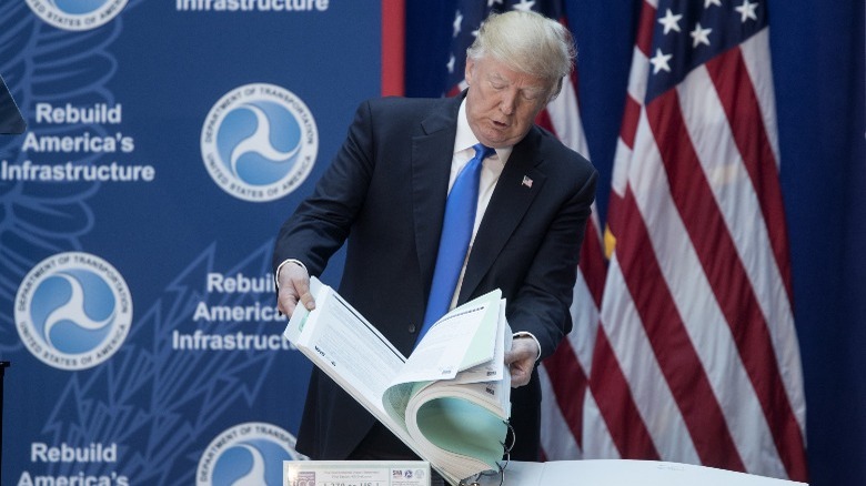 Donald Trump flipping through a large binder