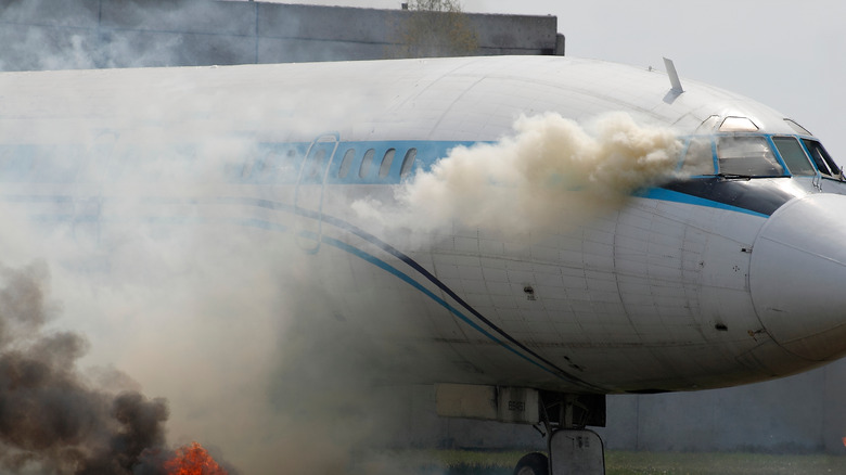 Commercial airplane engulfed in smoke at an airport