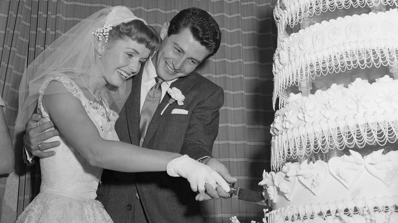 Eddie Fisher and Debbie Reynolds cutting their wedding cake