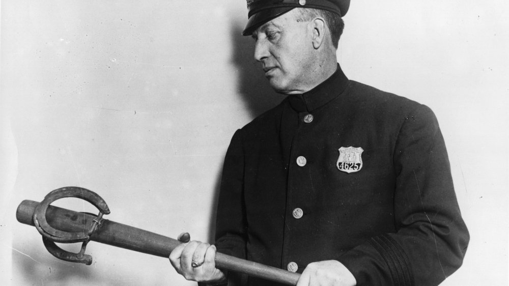 A policeman holding a baseball bat with a horseshoe attached to the end. It is one of the exhibits in the crime museum at New York's Police College. 