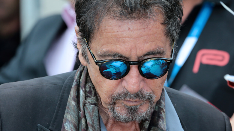 His sunglasses reflect Al Pacino's hands as he signs autographs