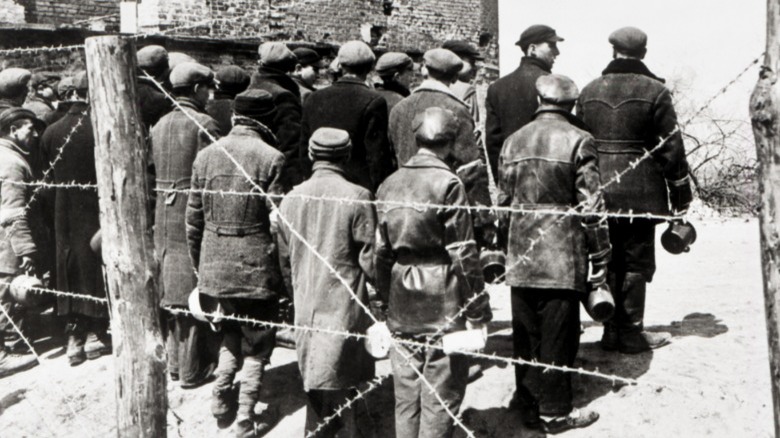 Jews standing together behind barbed wire