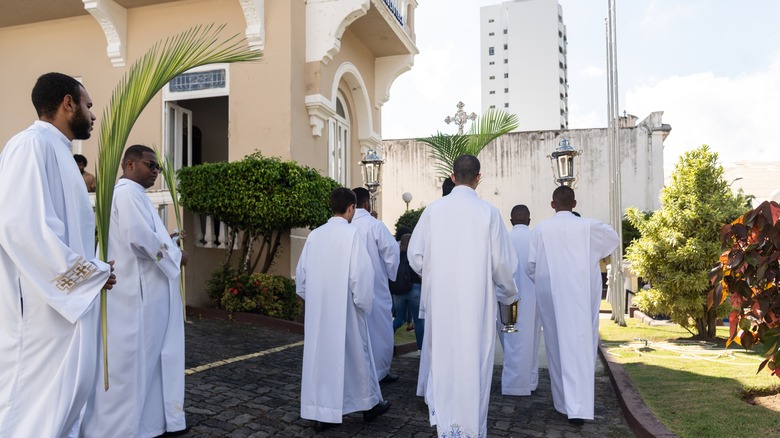 Brazilian seminarians white robes carrying crucifix procession