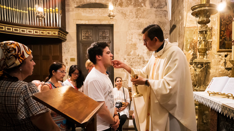 Priest gives communion to parishioner on tongue