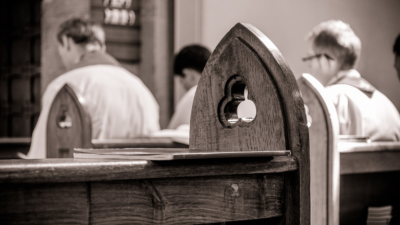 Priests praying in gothic pews