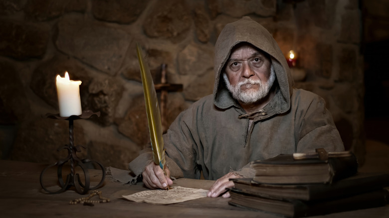 monastic scribe with candle and quill