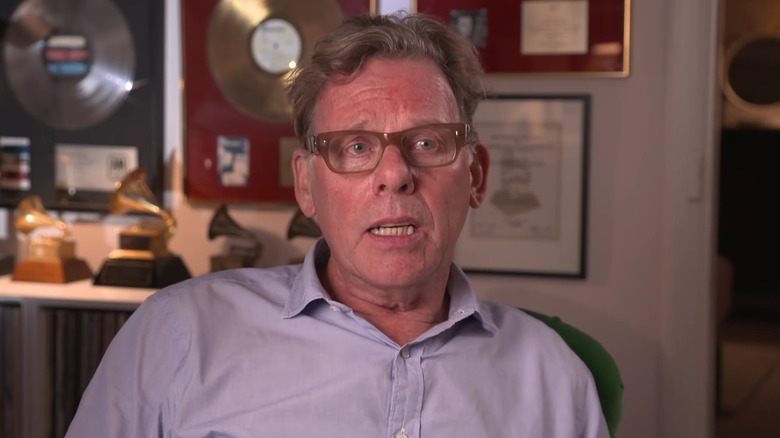 Hugh Padham seated with gold and platinum framed records in the background