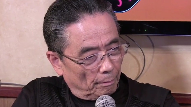 Tadao Kikumoto speaking into a microphone during an interview