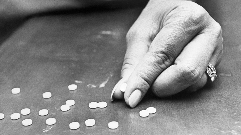 hand pinching thalidomide pills on table