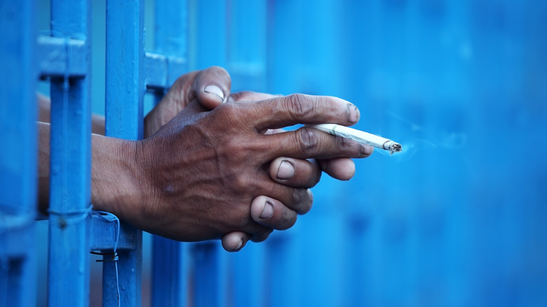 Hands behind bars holding cigarette