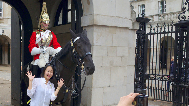 tourist posing in front of british military guard