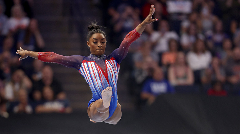 Simone biles mid-jump on balance beam