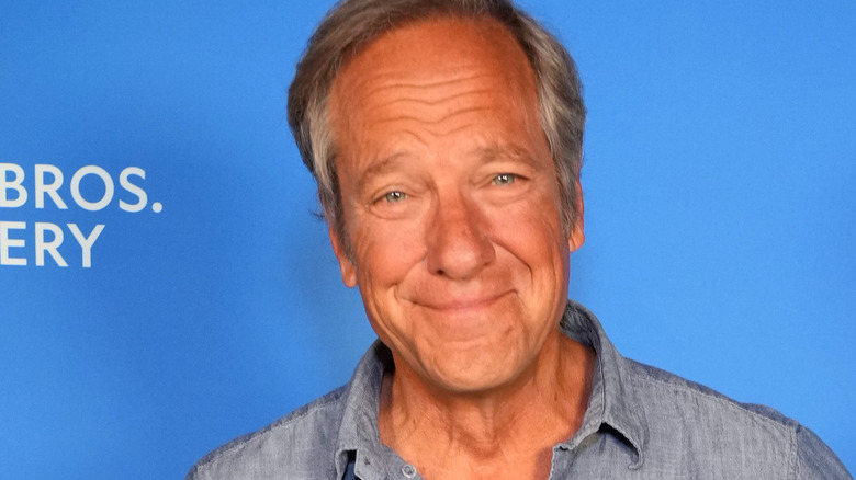 mike rowe wincing blue shirt blue backdrop