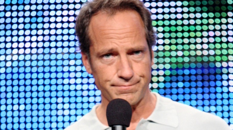 mike rowe smirking with microphone