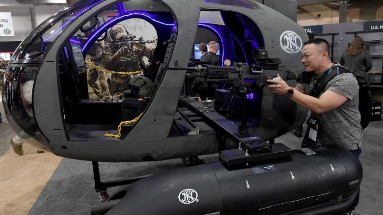 man with gun next to helicopter