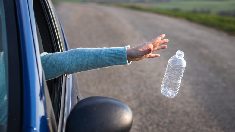 driver throwing plastic bottle out a car window