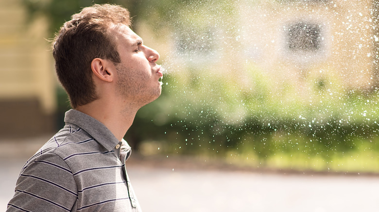 Man spitting beverage in public