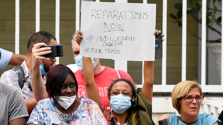 A protestor holds up a sign during Prince William's visit to Jamaica