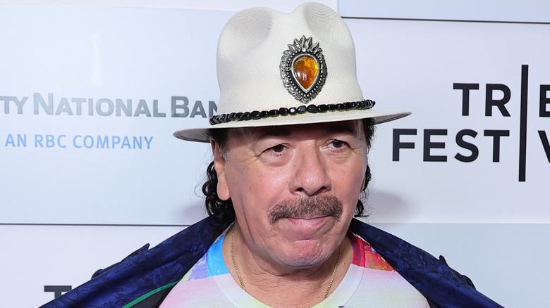 carlos santana pursing lips tie-dye shirt hat