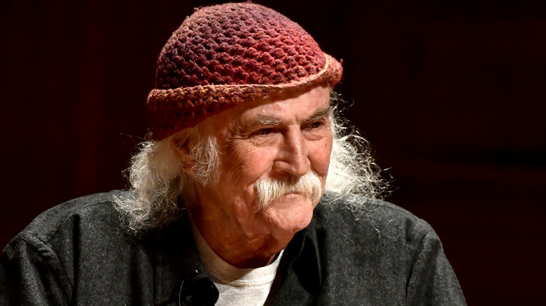 David Crosby frowning leaning forward red hat