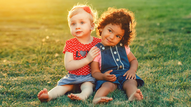 two toddler girls sitting in the grass