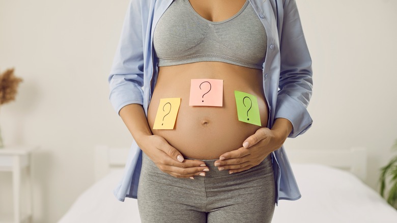 Pregnant woman with question mark notes