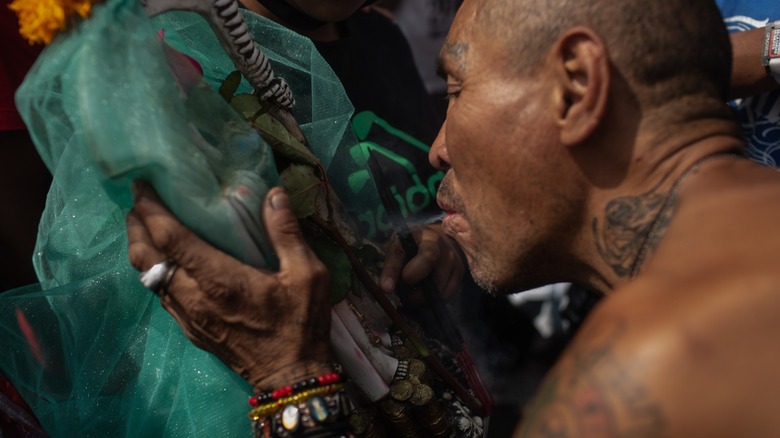 Man blowing smoke on Santa Muerte shrine