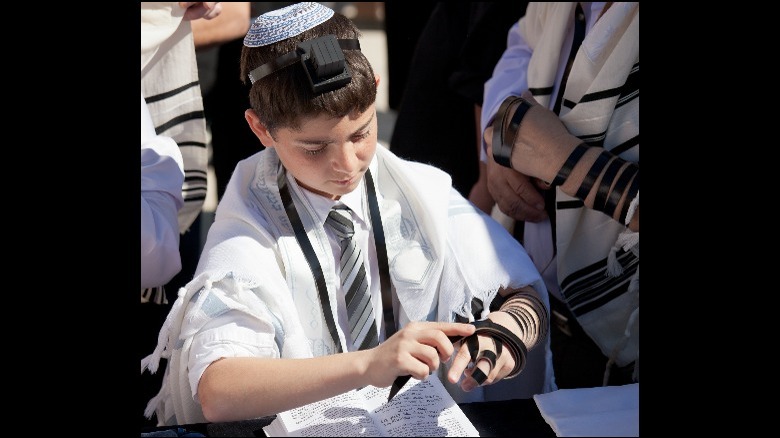 Jewish boy putting on tefillin