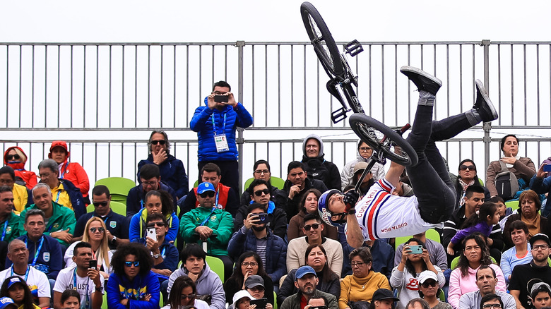 BMX freestyler performing stunt before crowd