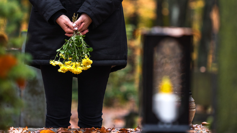 person holding flowers by grave