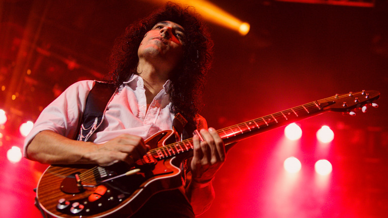 Brian May long black hair playing guitar