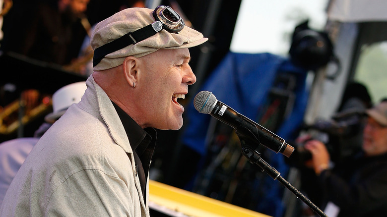 Thomas Dolby flat cap singing into microphone