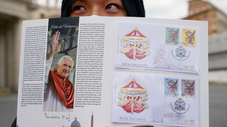 Woman displaying sede vacante stamps book