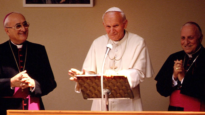 Pope John Paul II at lecturn white robe by cardinals