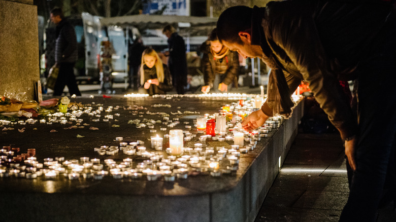 men and women light candles for paris attacks