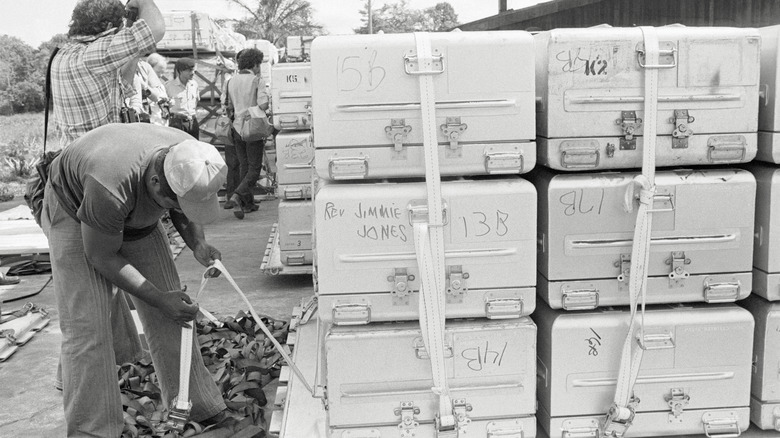 man secures stack of aluminum caskets from Jonestown