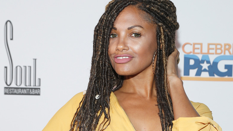 KD Aubert smiling posing at event yellow shirt