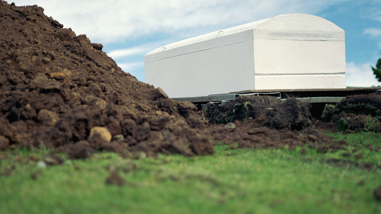 White coffin near open grave