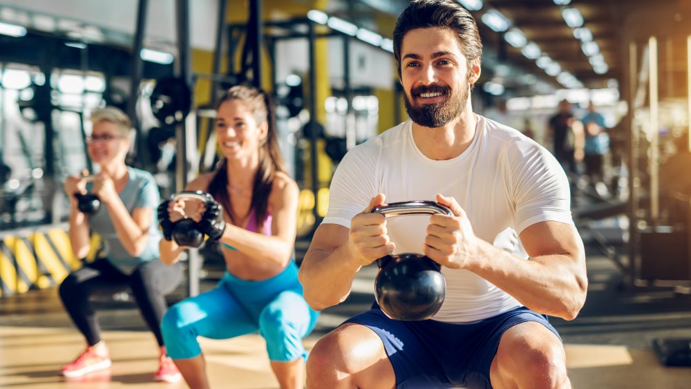 Man and two women doing squats in a fitness class