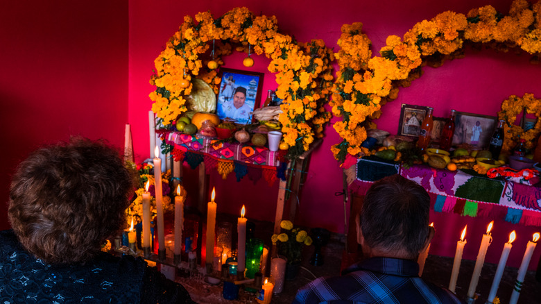 Mexican couple sits in front of an altar of the dead during the Day of the Dead celebrations on November 1, 2021 in Metlatónoc, Mexico