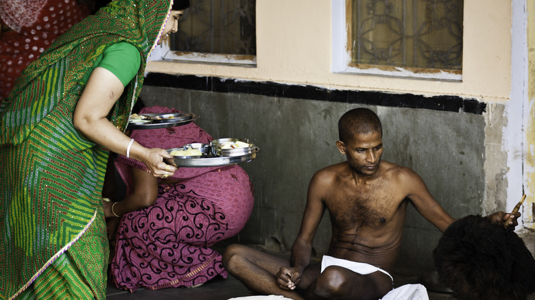 Woman in sari seated Jain monk