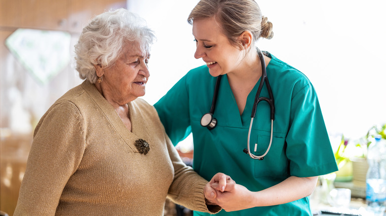 Nurse helps old woman walk