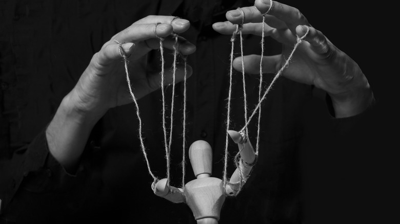 Hands controlling a puppet with string