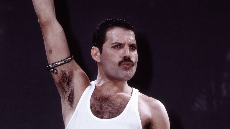 Freddie Mercury with arm upraised in white vest and armband