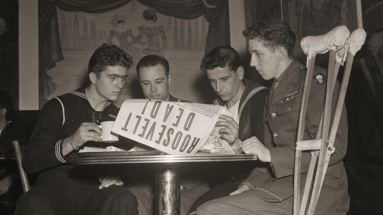 Four servicemembers reading newspaper announcing FDR's death